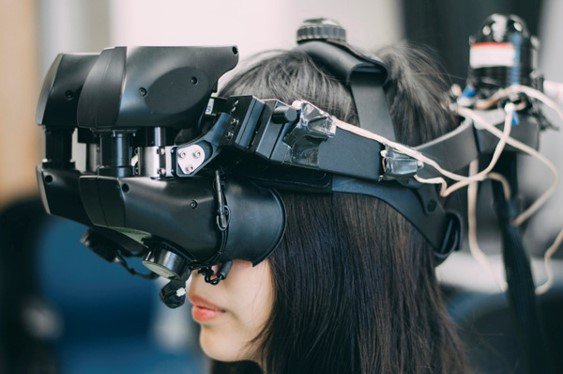 A person wearing a bulky, wired experimental head-mounted display.