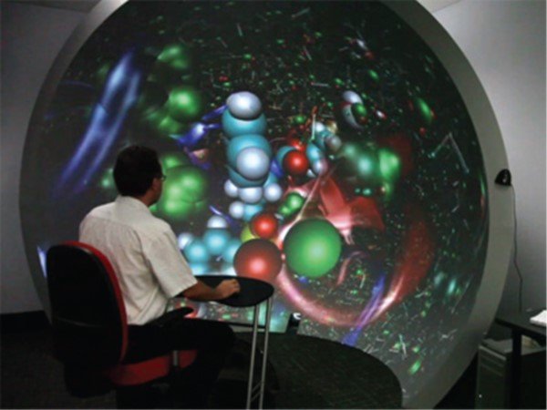 A person viewing an interactive molecular visualization on a hemispherical dome display.