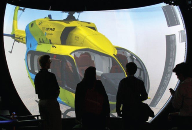 People viewing a helicopter model on a curved, rear-projected cylindrical surround-screen display.